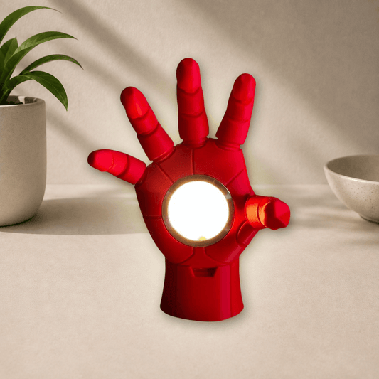 Red 3D-printed Iron Man hand-shaped lamp with its round palm light glowing warm white.