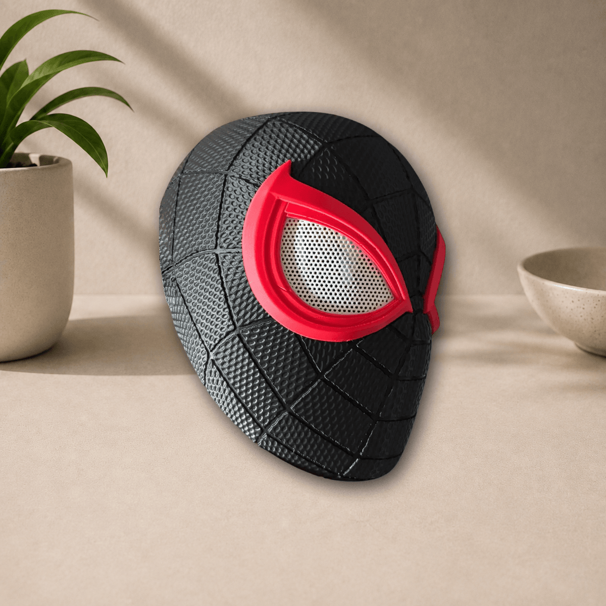 Side profile view of the black 3D-printed Miles Morales PS5 cosplay mask, showing its red eye trim and webbed texture.