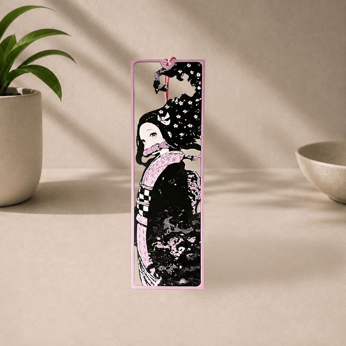 3D-printed Nezuko bookmark from Demon Slayer, showing her side profile in a pink floral kimono with a purple tassel.