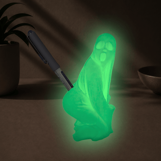 Glow-in-the-dark green twerking ghost pen holder glowing in a dark room, holding a pen