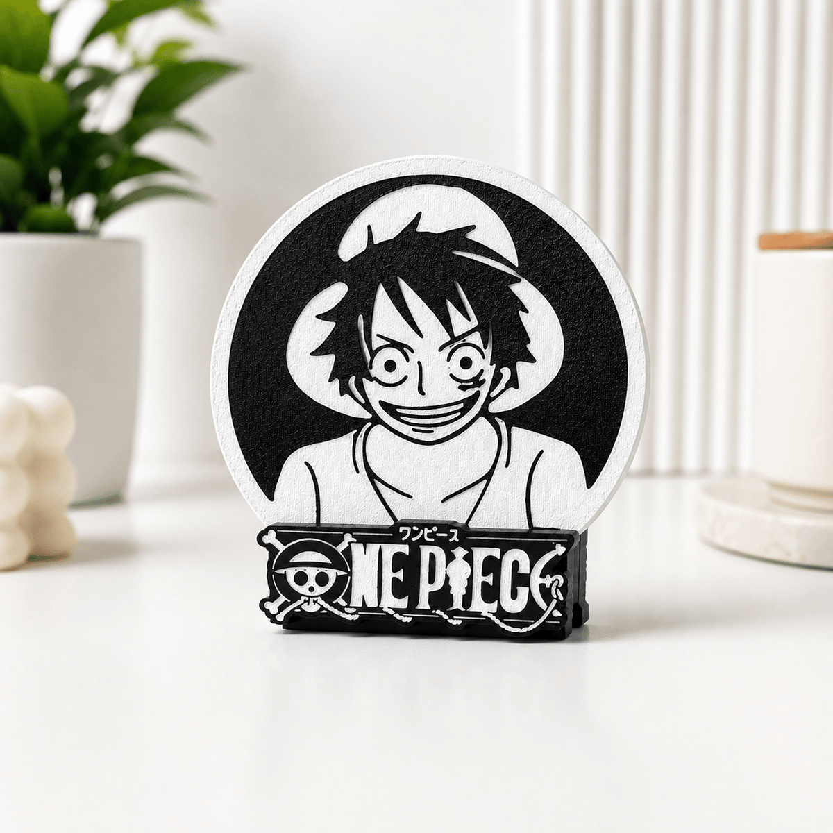 3D-printed One Piece coaster featuring a black-and-white Luffy design displayed upright in its branded One Piece stand on a desk.