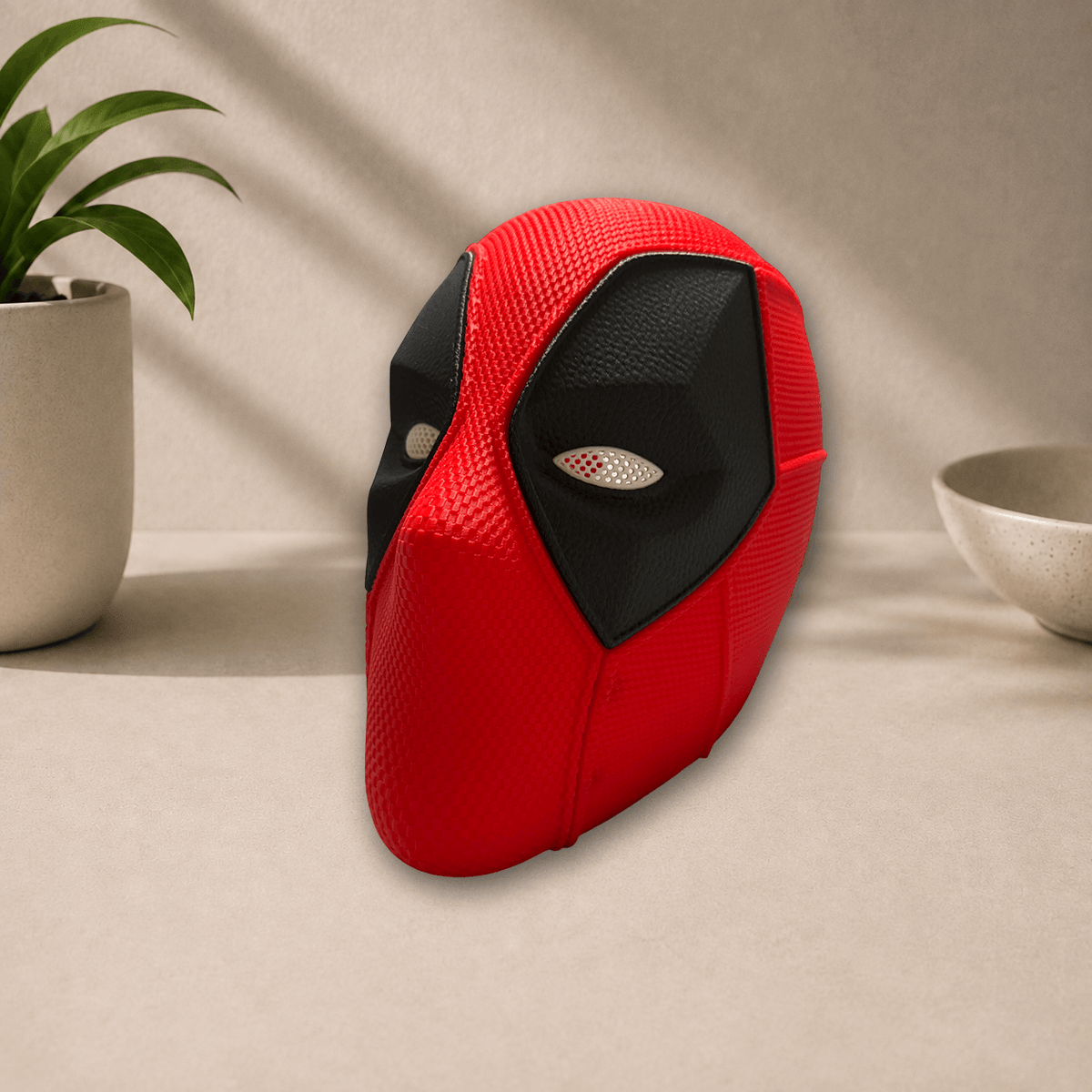 Side profile view of the red and black 3D-printed Deadpool cosplay mask, showing its angular eye lens and textured surface.