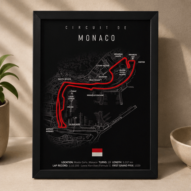 Black-framed 3D-printed Circuit de Monaco F1 track print with a red highlighted route, standing upright on a table beside a potted plant.