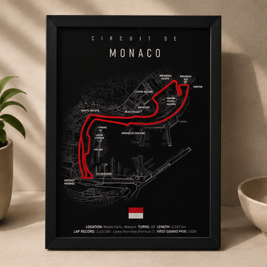 Black-framed 3D-printed Circuit de Monaco F1 track print with a red highlighted route, standing upright on a table beside a potted plant.