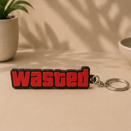 Red and black 'WASTED' text keychain inspired by GTA V, shown front-on on a beige tabletop.