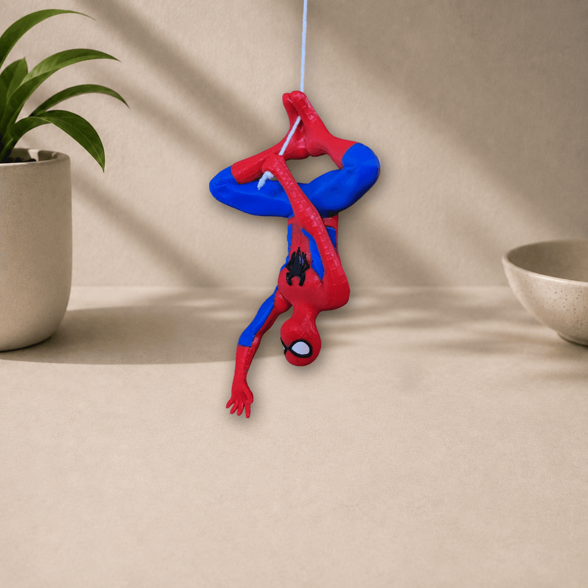 Angled view of the red and blue 3D-printed hanging Spider-Man wall decor figure in its upside-down web-slinging pose.