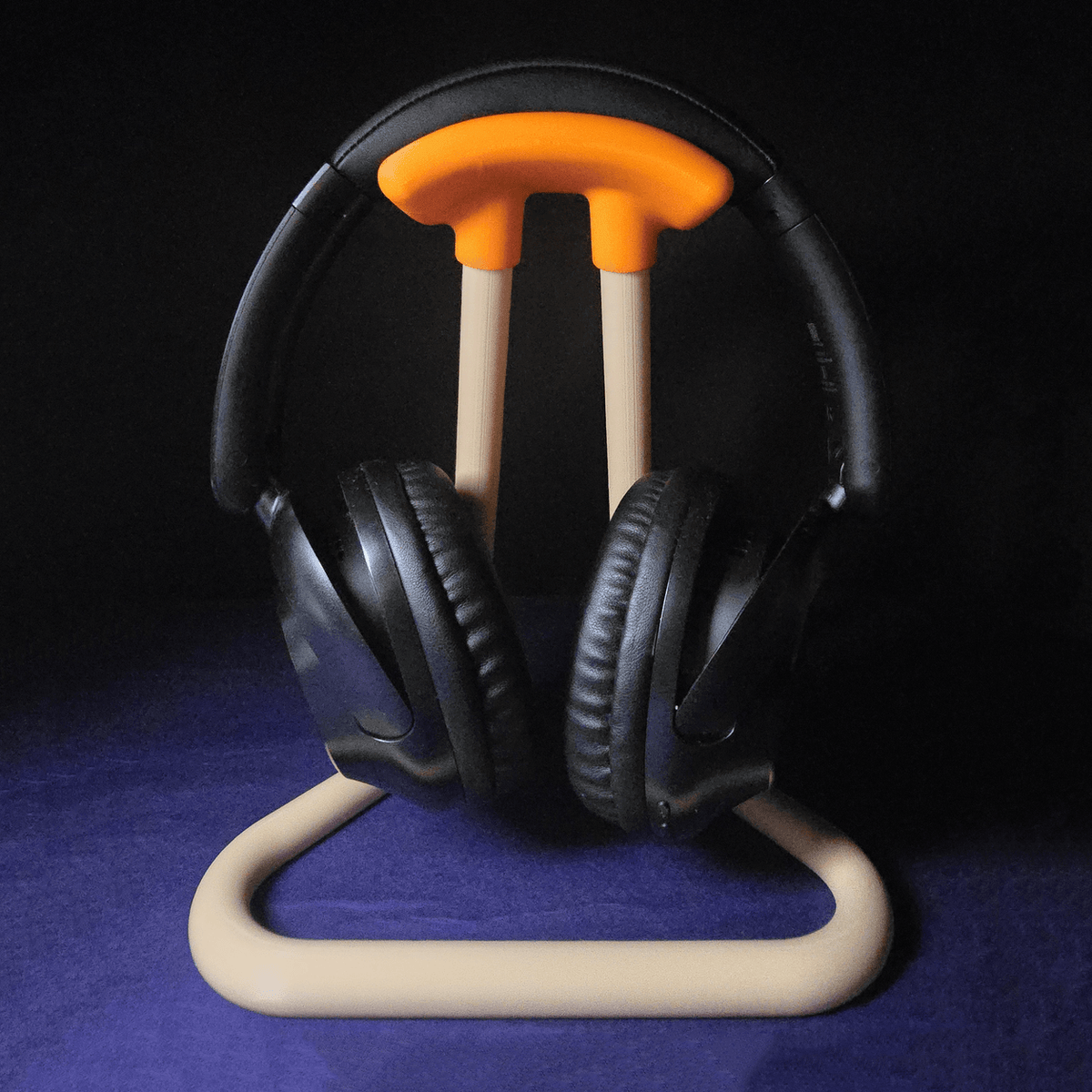 Close-up front view of the headphone stand with headphones mounted, dramatic dark studio lighting