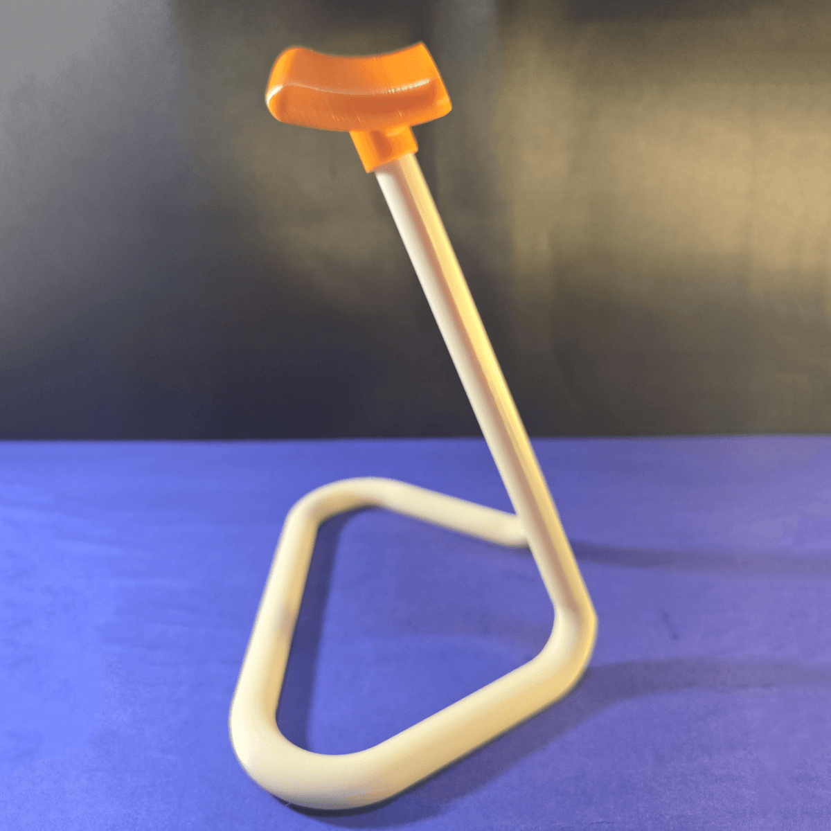 Full side view of the empty 3D-printed headphone stand showing its curved base and orange grip
