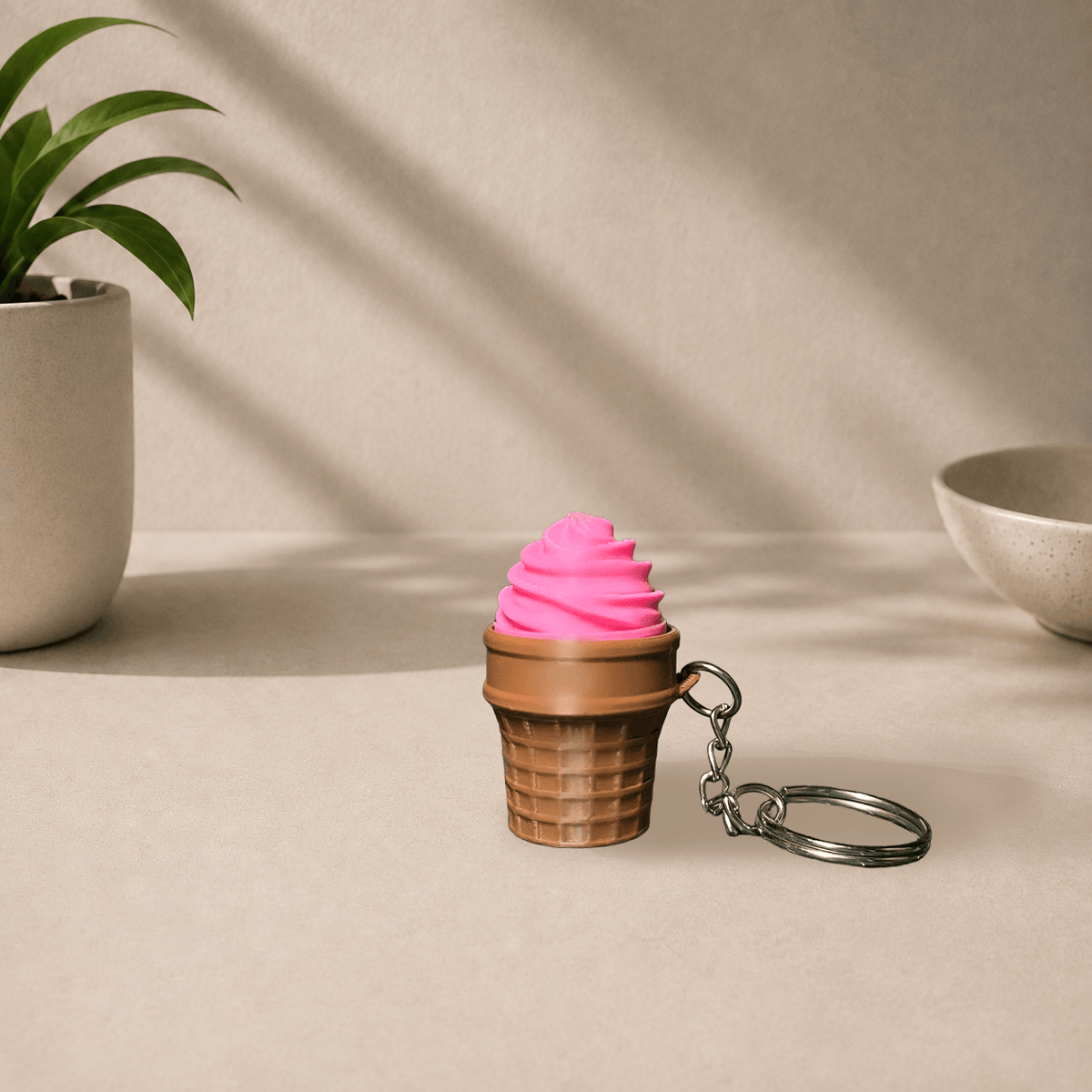 3D-printed ice cream cone keychain with a pink swirl scoop on a brown waffle cone, hanging from a metal keyring.