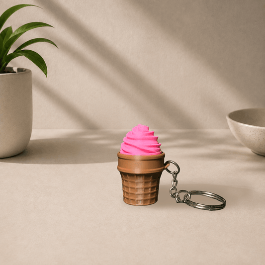 3D-printed ice cream cone keychain with a pink swirl scoop on a brown waffle cone, hanging from a metal keyring.
