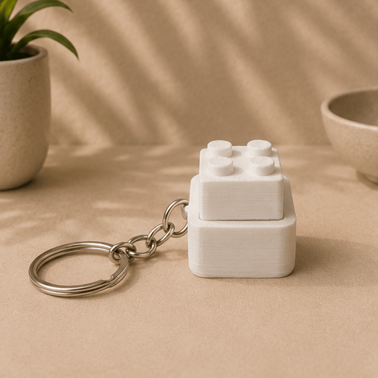 White 3D-printed Lego-brick-style fidget keychain with its top block pressed down, front view.