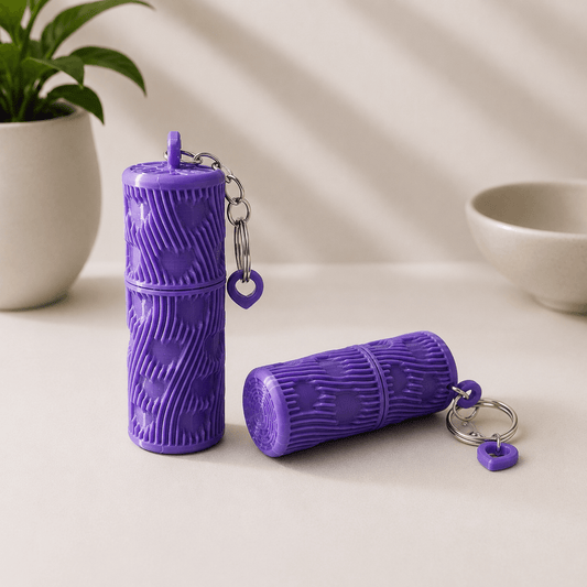 Two purple 3D-printed ribbed Lipstick Holder Keychains with heart-shaped charms, one standing upright and one lying on its side.