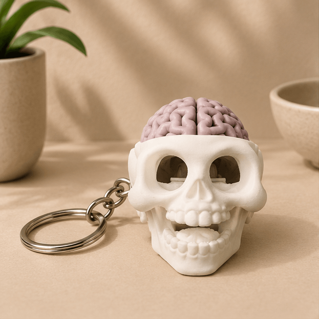White skull fidget keychain with a pink brain sitting on top, front-facing view on a beige tabletop.