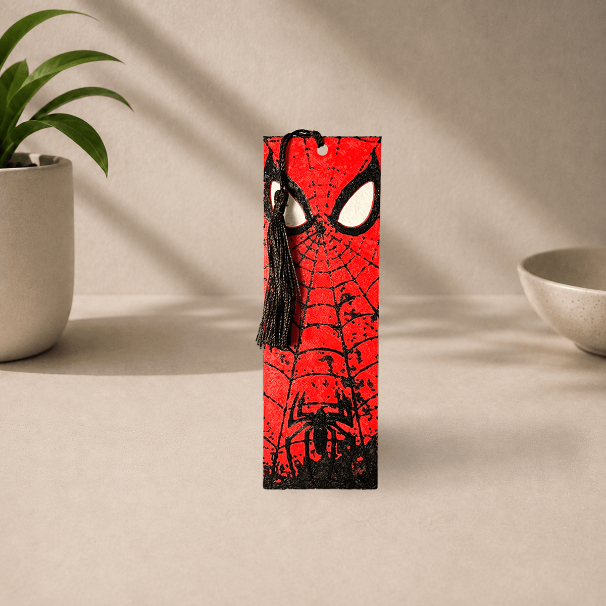 3D-printed Spider-Man bookmark with a red web-patterned mask design and a black tassel.