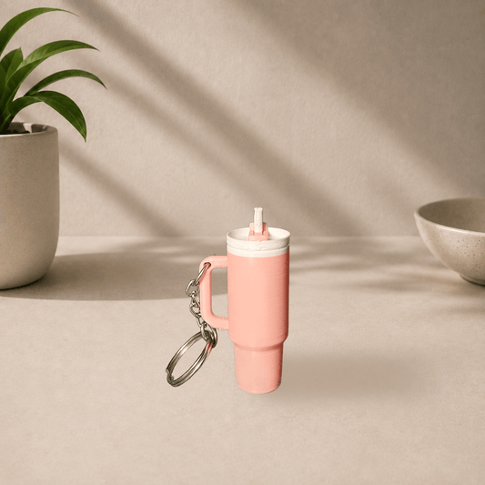Baby pink 3D-printed Stanley cup-style tumbler keychain with a straw and handle, hanging from a metal keyring.