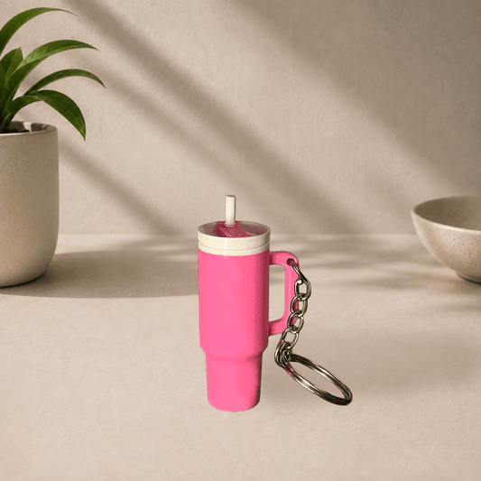 Pink 3D-printed Stanley cup-style tumbler keychain with a straw and handle, hanging from a metal keyring.