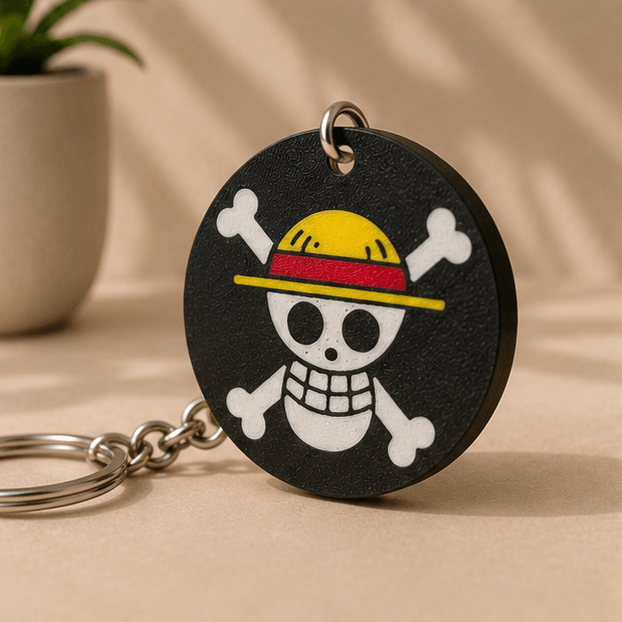 Close-up of the round black Jolly Roger skull-and-crossbones charm from the One Piece Straw Hat Keychain set.