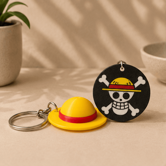 One Piece Straw Hat Keychain set, showing the yellow straw hat charm next to the round black Jolly Roger skull-and-crossbones charm.