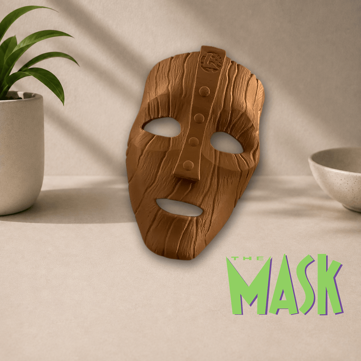 3D-printed 'The Mask' cosplay display mask in a matte wood-grain brown finish, shown beside The Mask movie logo.