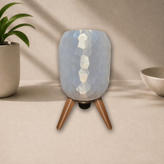 3D-printed tripod table lamp with a pebble-textured white shade on dark bronze tripod legs, unlit, front view on a beige tabletop.
